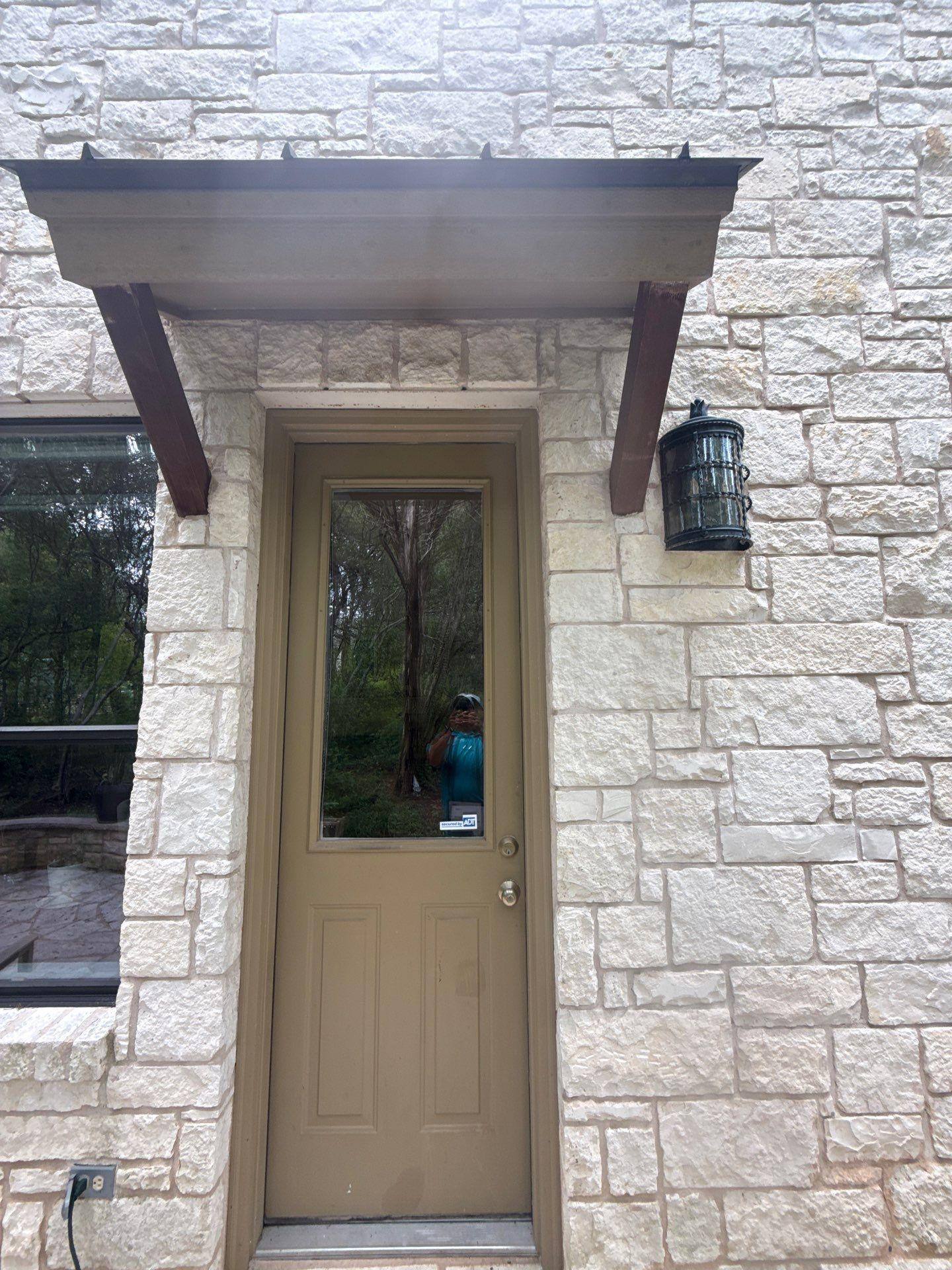 Arched stone entry door of a home on Gregory Pl in Austin, TX prepared for an exterior painting estimate by Hill Country Painting