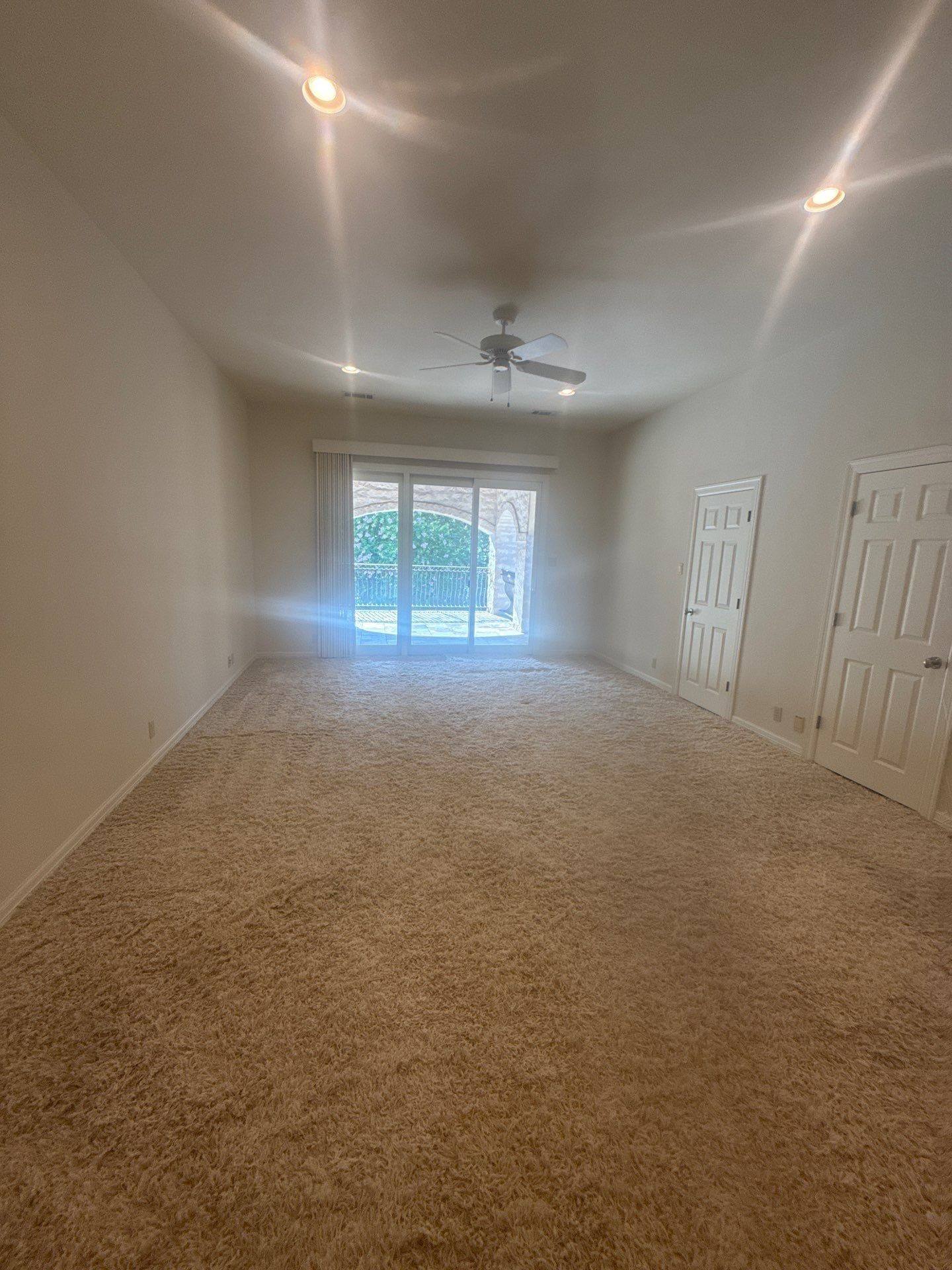 Bedroom with carpet and balcony access at a property on Lakeway Hills Cv in Lakeway, TX ahead of whole-home interior painting by Hill Country Painting