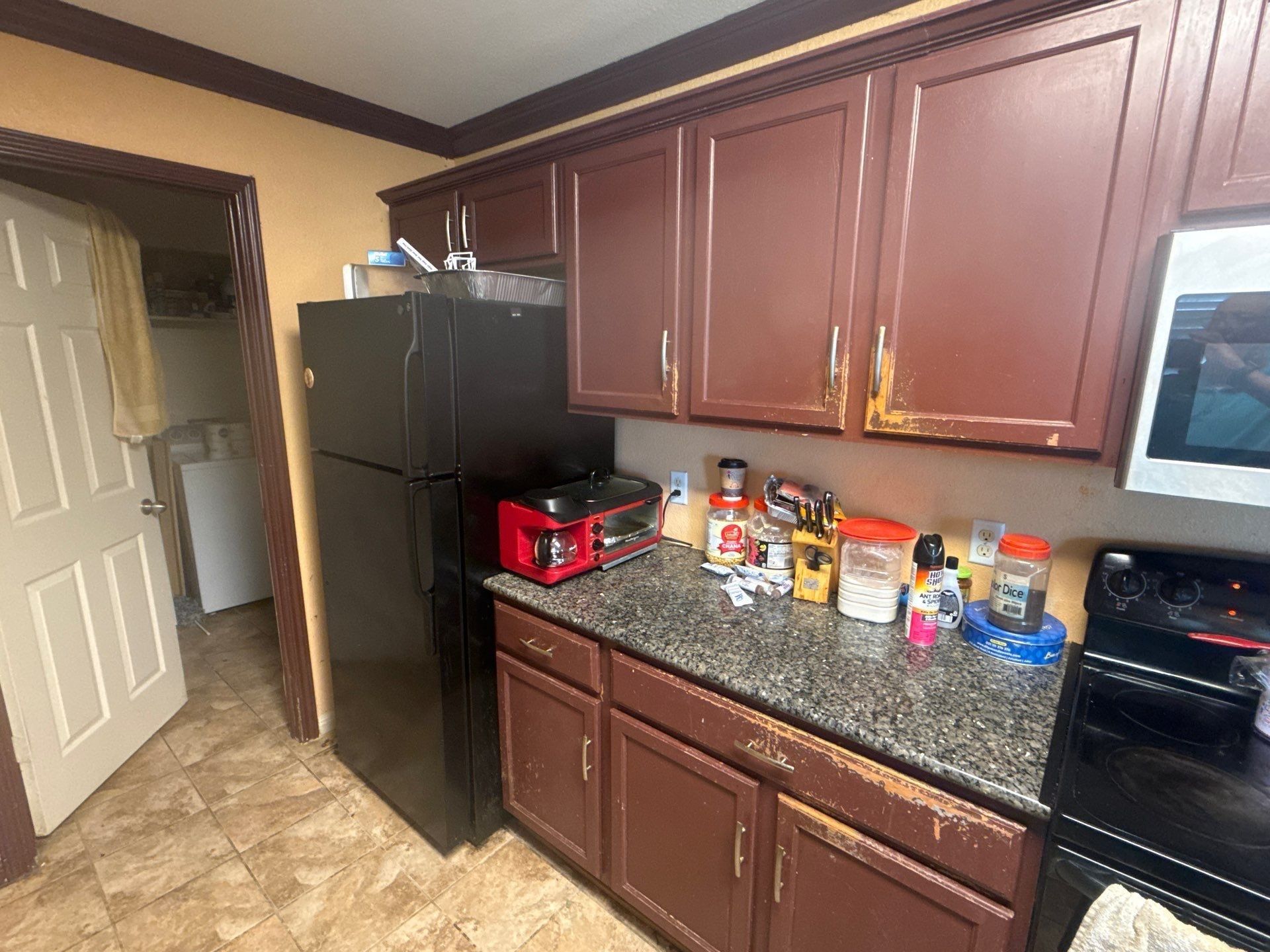 Kitchen cabinets at a property on Pine Needle St in Manor, TX ahead of cabinet refinishing by Hill Country Painting