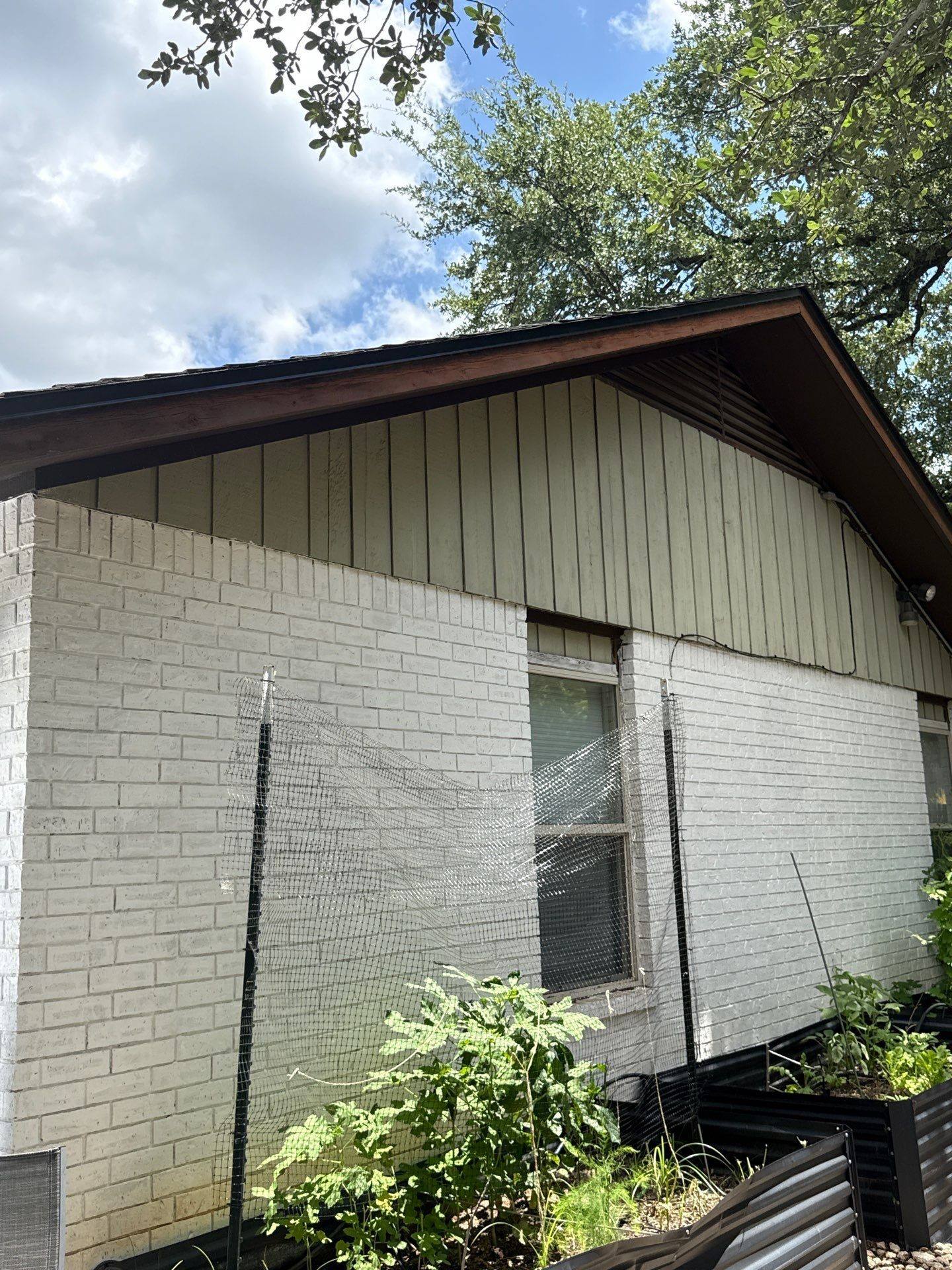 Side exterior of the home ahead of painting, showing brick and gable