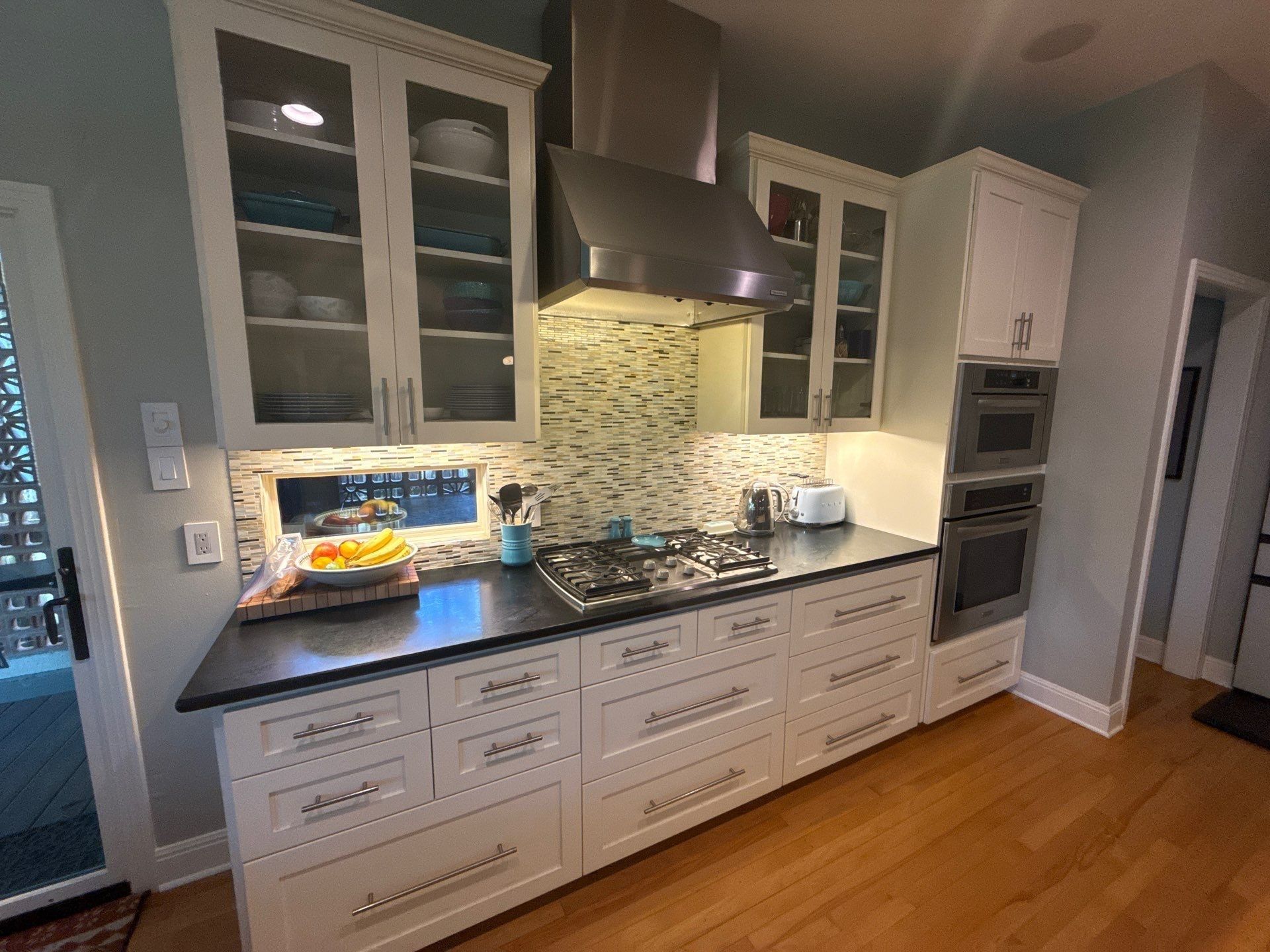 Wide view of kitchen cabinets, drawers, and stovetop ahead of painting