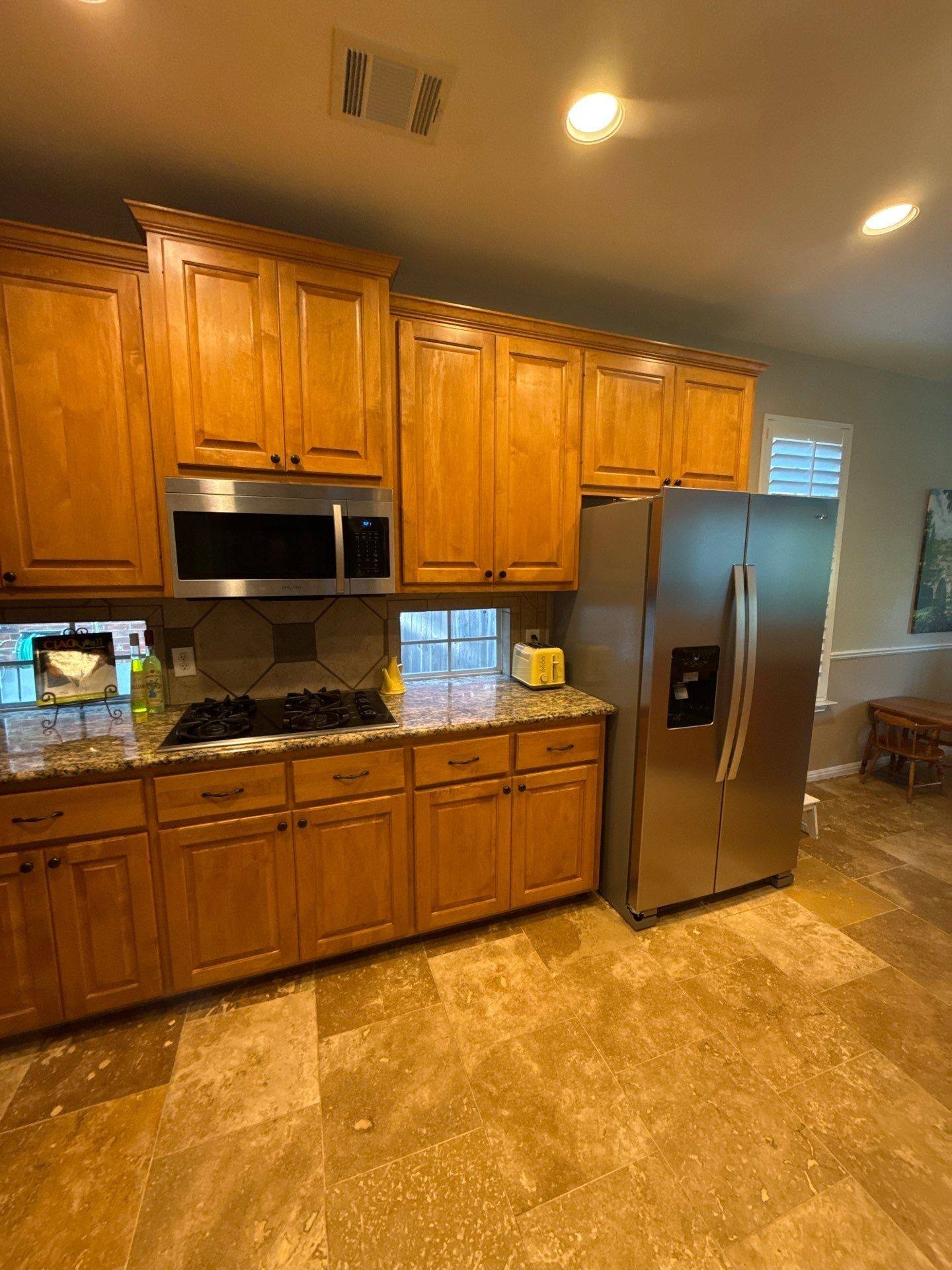 Wide view of kitchen cabinets, refrigerator, and stovetop ahead of painting
