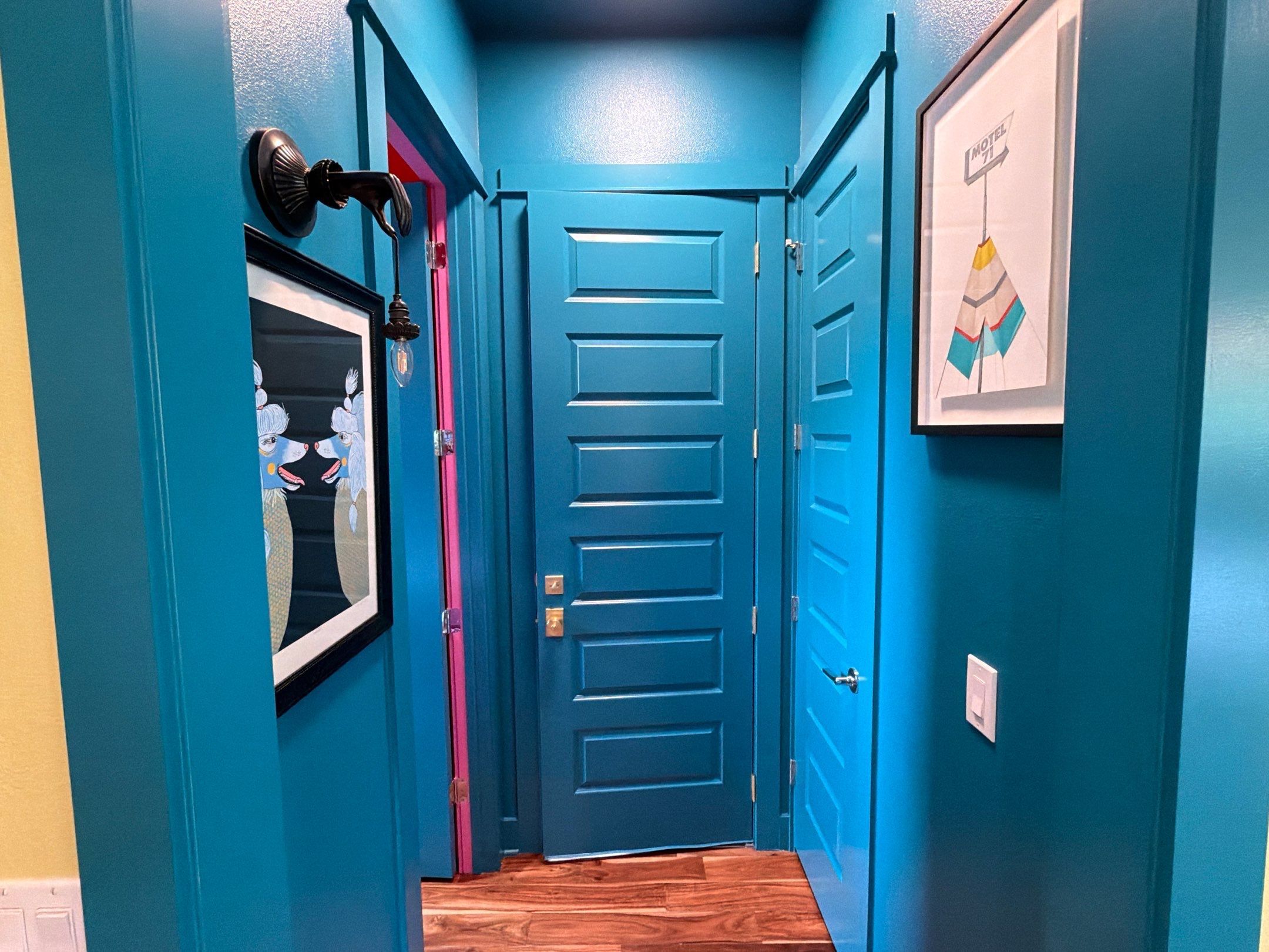 Teal hallway with pink door trim in the Bee Cave home