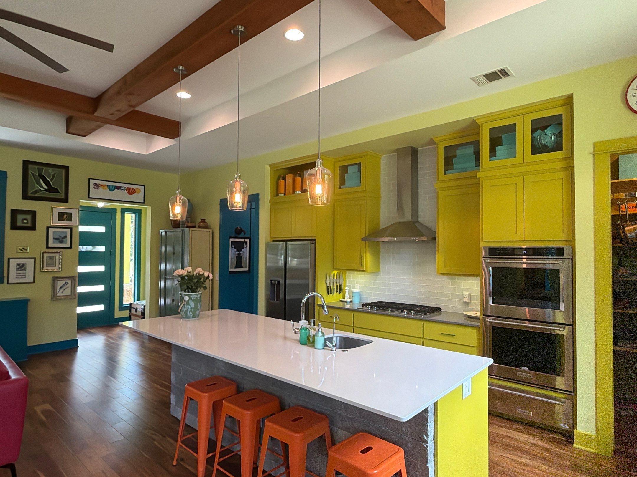 Bright yellow kitchen with island and orange stools in the Bee Cave home