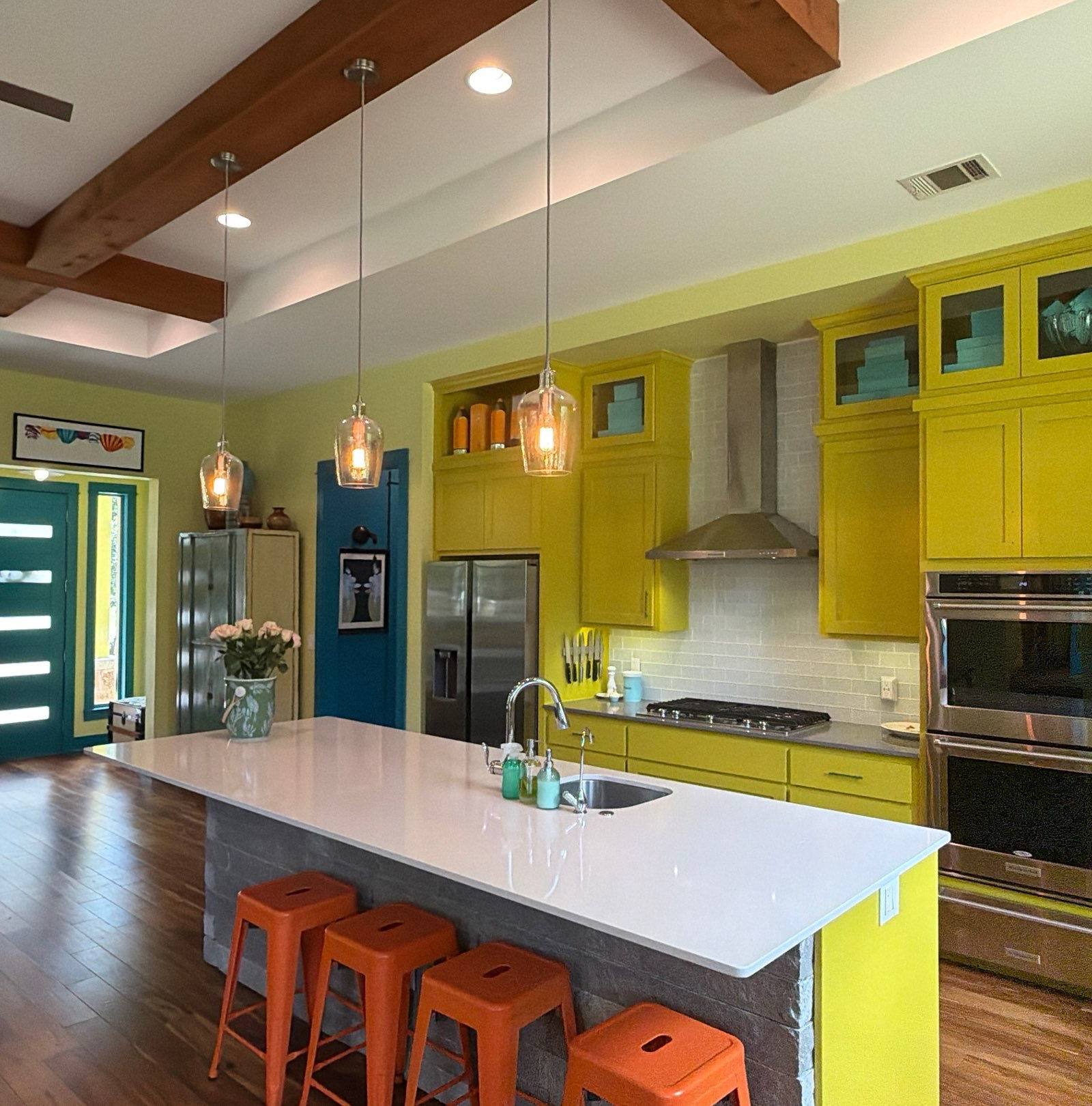 Bright yellow kitchen with island and orange stools in the Bee Cave home