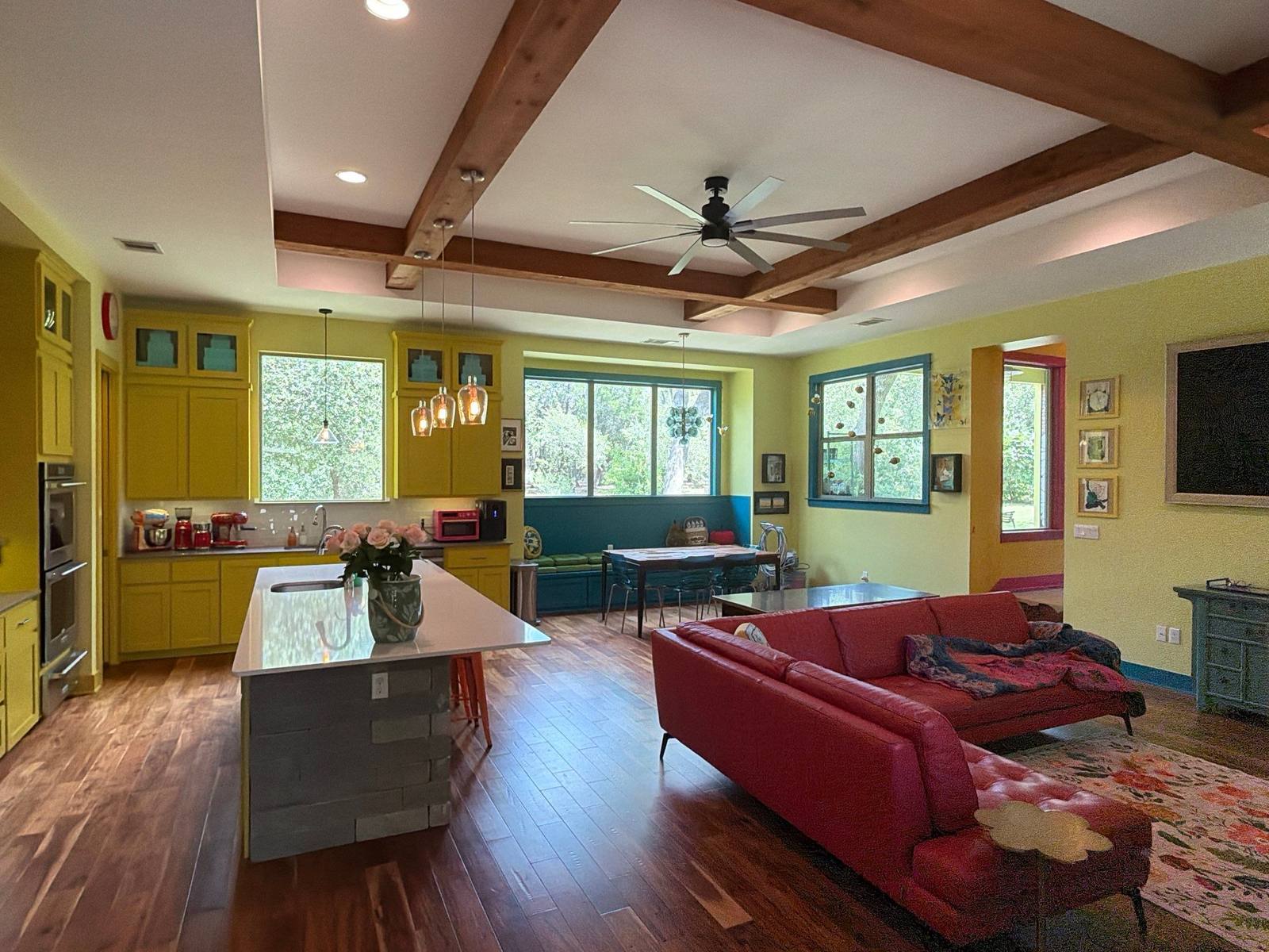 Chartreuse living room with red sofa opening onto the yellow kitchen in the Bee Cave home