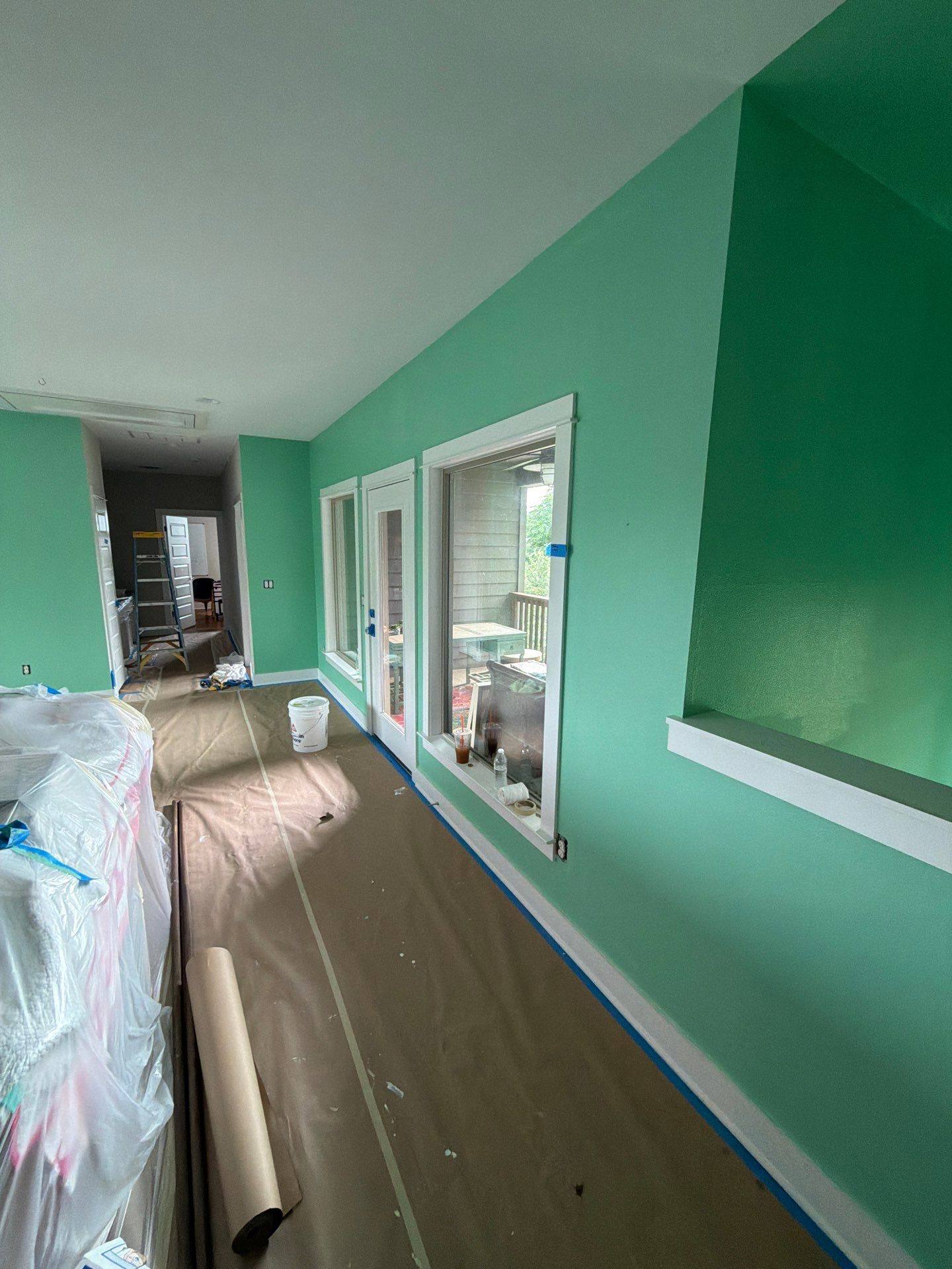 Fresh mint-green room mid-project with floor and furniture protection in place